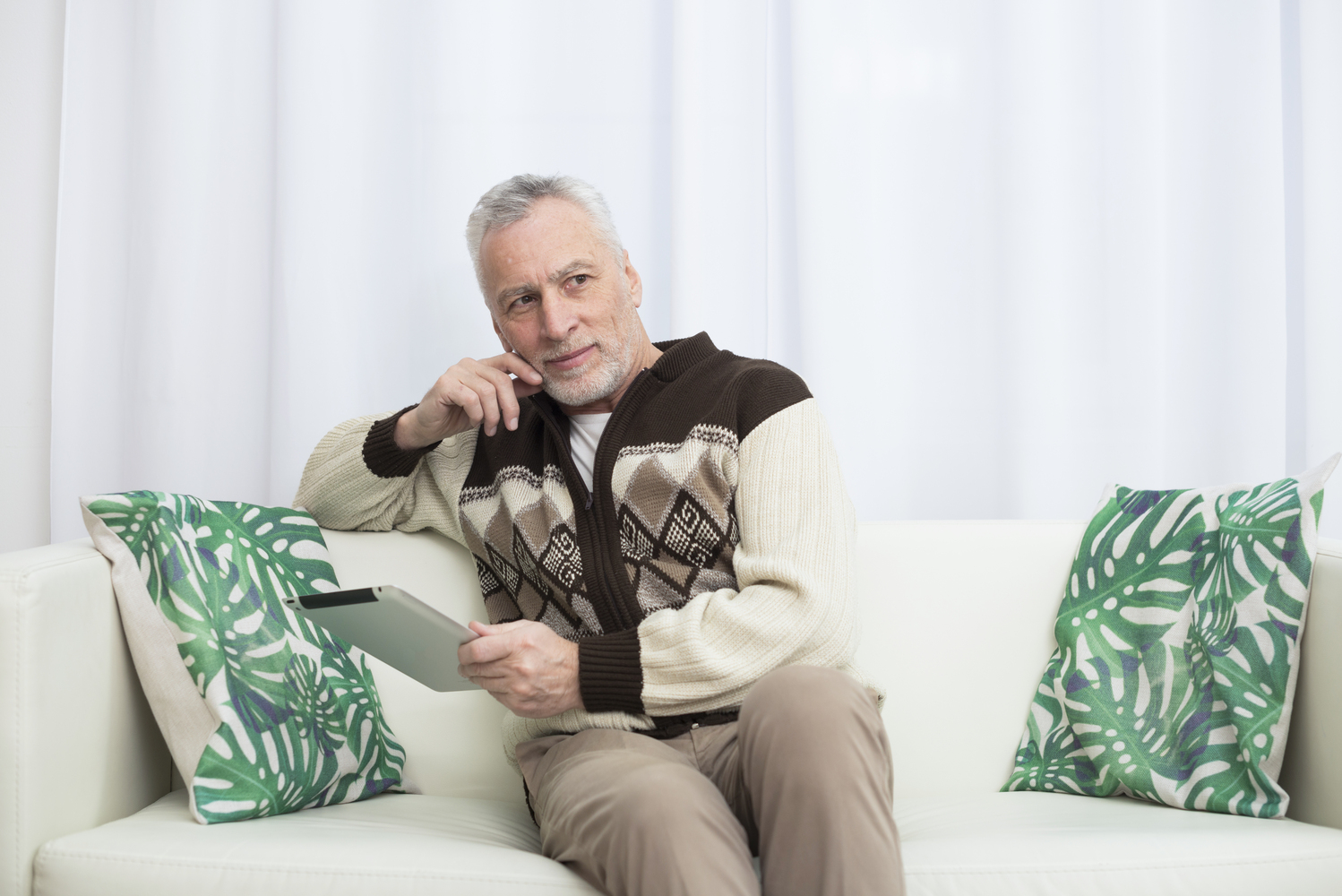Мужчина пенсионер сидит на диване и отдыхает от своего нового хобби