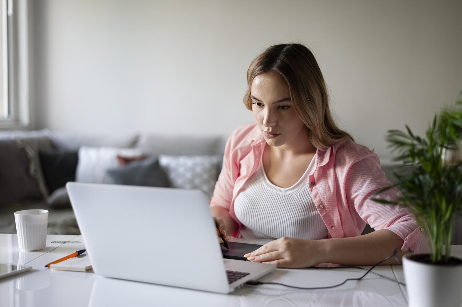 девушка сидит в комнате за ноутбуком и изучает топ-10 онлайн профессий